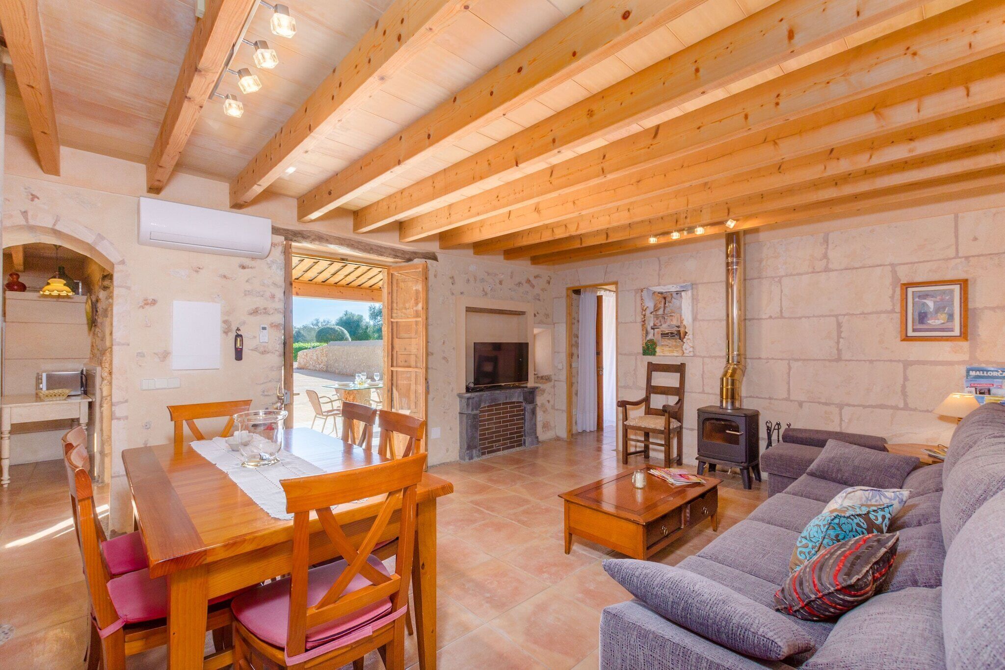 Un amplio salón con una mesa de comedor de madera, sillas, un sofá y una chimenea.