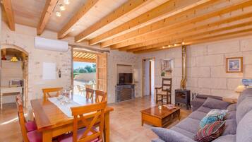 Un amplio salón con una mesa de comedor de madera, sillas, un sofá y una chimenea.