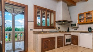 A kitchen with wooden cabinets, a microwave, an oven, and a dishwasher. - Ca'n Berguins - Villa With Private Pool In Búger (Buger, Illes Balears)