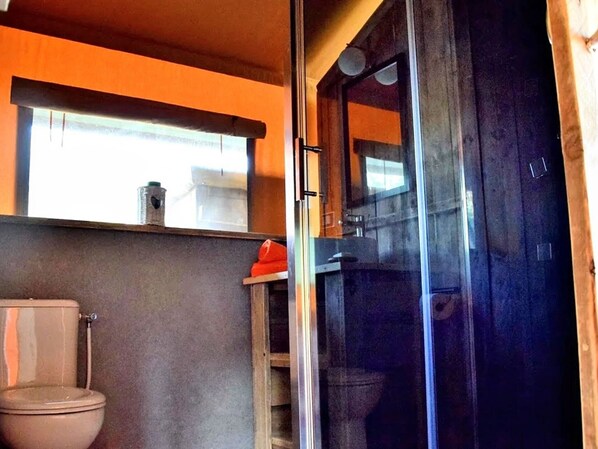 A bathroom with a toilet, a glass shower enclosure, and a wooden shelf above the toilet. - Luxury Glamping Near Adriatic Beaches (Lapedona)
