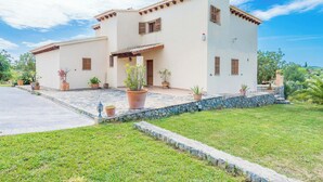 Una casa a due piani con un vialetto in pietra che conduce all'ingresso, circondata da un prato curato e piante in vaso.