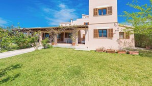 Une maison moderne à deux étages, dotée d’un patio couvert, d’une pelouse bien entretenue et de plantes en pot.