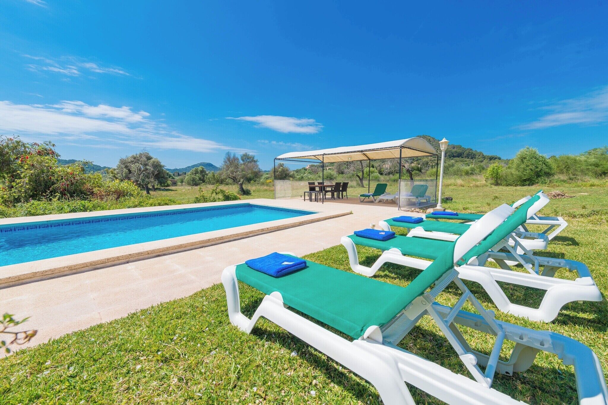 A pool area with lounge chairs and a covered seating area.