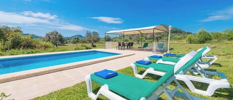 A pool area with lounge chairs and a covered seating area.