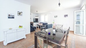 Een moderne woonkamer met een eettafel, bank en televisie.