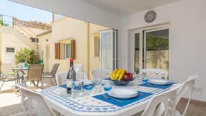 A dining area with a table set for four, including a bowl of fruit, plates, and glasses.