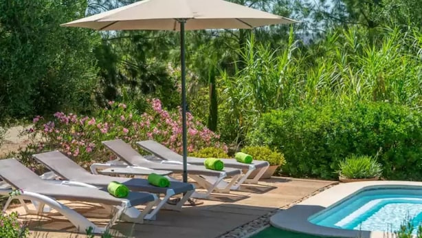 Zona junto a la piscina con sillones de descanso y una piscina.