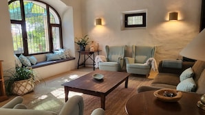 Una sala de estar acogedora con un amplio ventanal de arco, una mesa de centro de madera y dos sillones.
