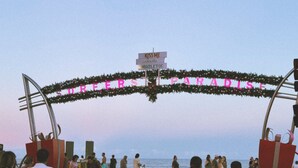 A beach entrance with a sign reading "KISS ME under the mistletoe" and "REFRESH PARADISE".