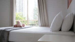 A hotel room with a bed, a balcony, and a view of a tall building.