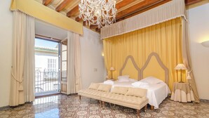 A hotel room with a bed, two bedside tables, a chandelier, and a patterned floor.