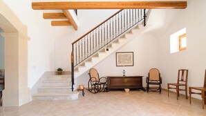 Une pièce spacieuse avec un escalier, un banc en bois et une petite table.