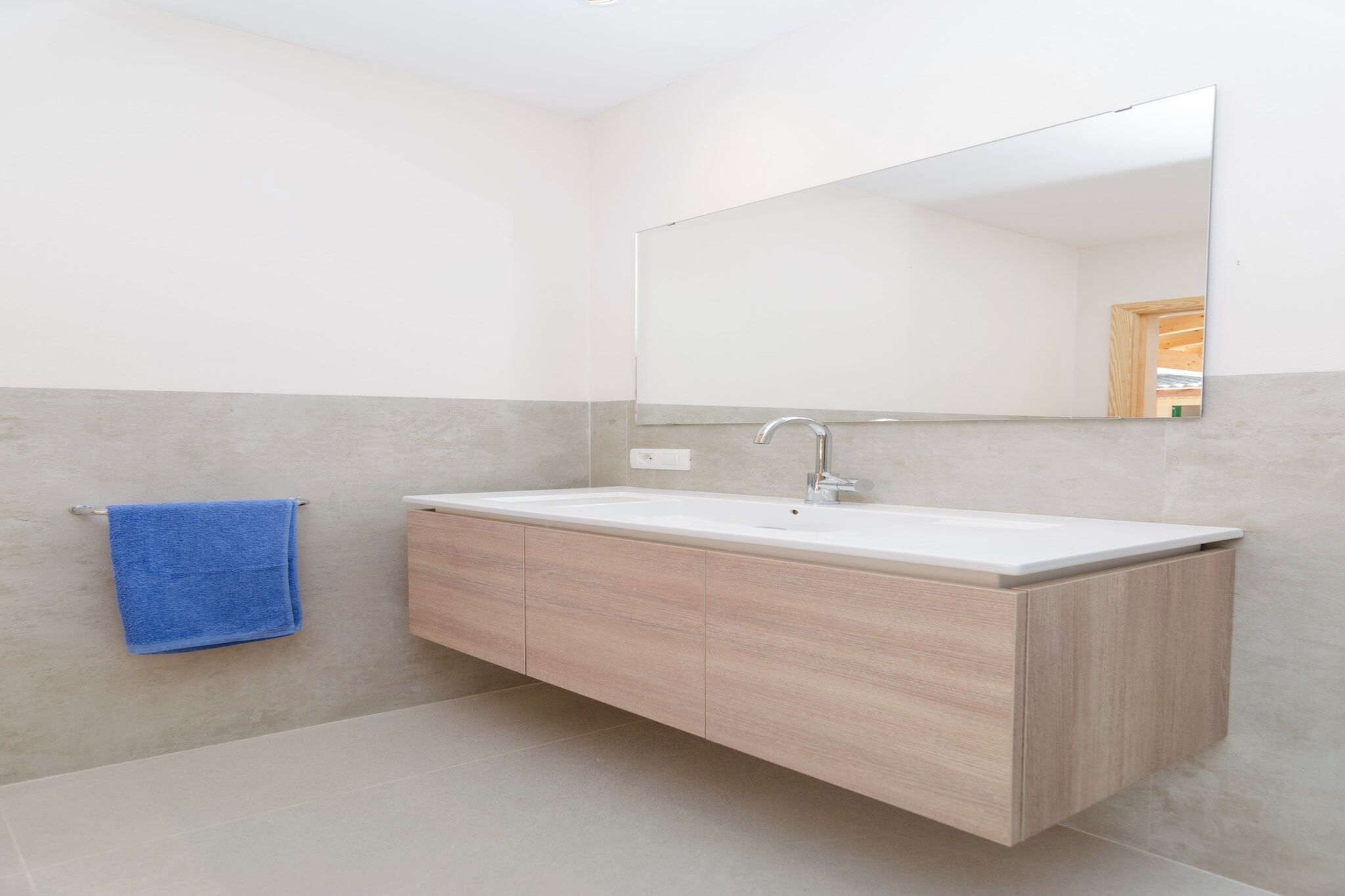 Een moderne badkamer met een grote spiegel, een wastafel en een handdoekhouder.