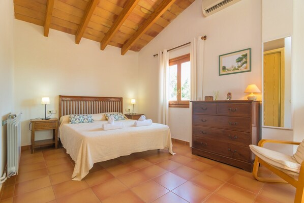 A bedroom with a bed, wooden headboard, bedside tables with lamps, a dresser, and a chair.