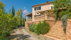 A two-story house with a stone facade, a balcony with plants, and a stone staircase leading to the entrance. - Es Garroveral 3  - Villa With Private Pool (Bunyola, Illes Balears)