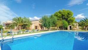 A swimming pool with lounge chairs and a stone building in the background.