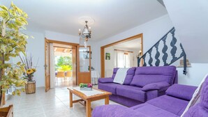 A living room with a purple sofa, a wooden coffee table, and a chandelier.