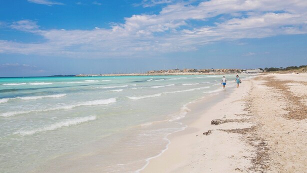 A beach with clear turquoise waters and a sandy shore.