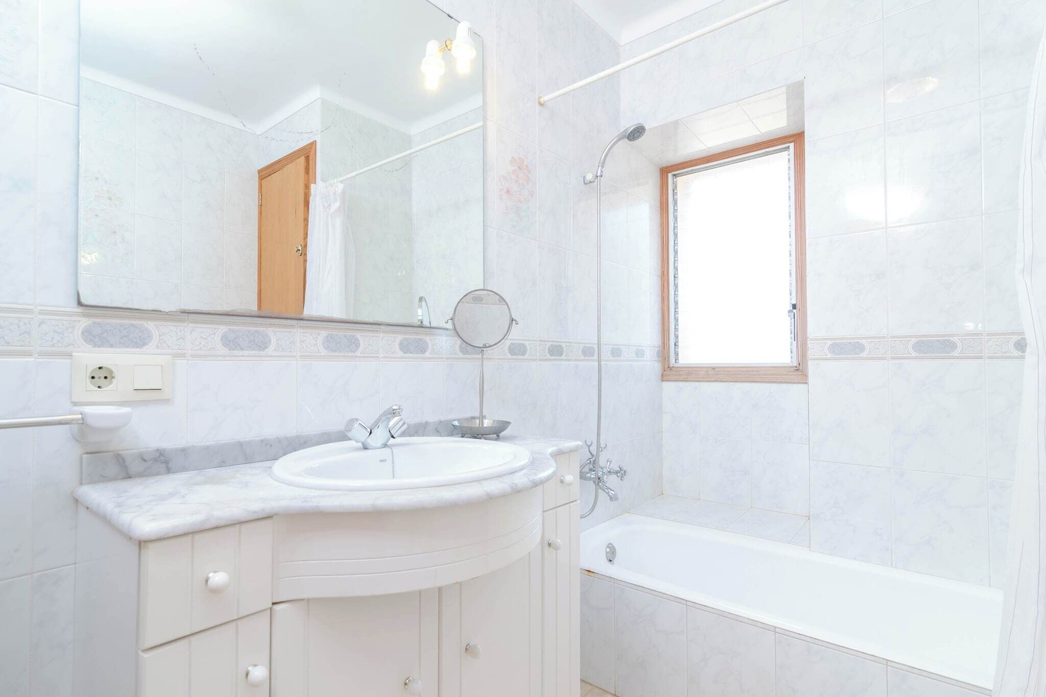 A bathroom with a sink, mirror, and bathtub.