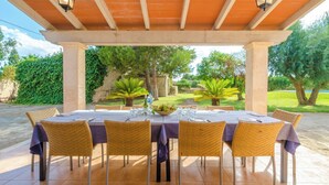 An outdoor dining area with a covered pergola, a table set for six, and wicker chairs.