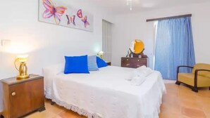 A hotel room with a bed, a nightstand, a lamp, a chair, a mirror, and a window with curtains. - Can Salas - Apartment In Porreres. Free Wifi (Porreres, Illes Balears)