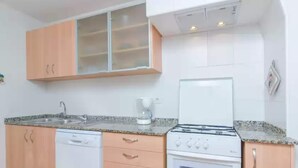 A compact kitchen with a dishwasher, stove, and a coffee maker. - Can Salas - Apartment In Porreres. Free Wifi (Porreres, Illes Balears)