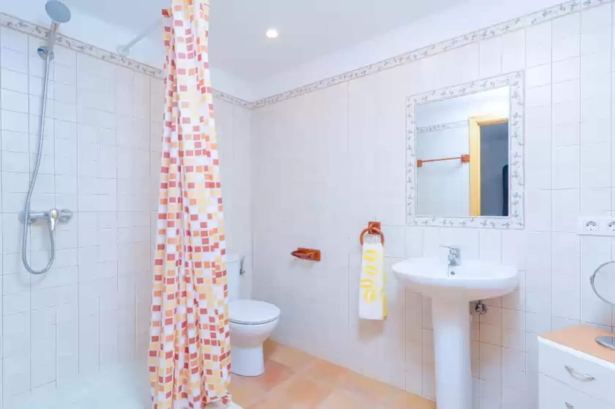 A bathroom with a shower, toilet, sink, and a mirror.