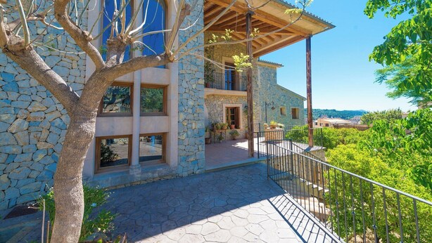 A stone house with a balcony, large windows, and a view of the surrounding landscape. - Turixant Dalt - Villa With Private Pool. Free Wifi (Mancor De La Vall, Illes Balears)