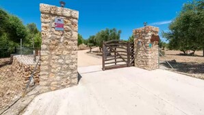 A stone gate with a sign, leading to a paved area with trees. - Son Vador - Villa With Private Pool. Free Wifi (Santa Margalida, Illes Balears)
