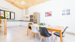 A spacious kitchen with white cabinets, a wooden dining table, and modern appliances. - Son Vador - Villa With Private Pool. Free Wifi (Santa Margalida, Illes Balears)