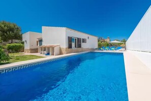 Une piscine avec un bâtiment blanc et une zone abritée à proximité.