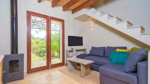 A living room with a sofa, a TV, a fireplace, and a staircase. - Can Pina - Eco Redonda 1 - - Apartment In Costitx (Costitx, Illes Balears)