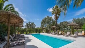A swimming pool with lounge chairs and thatched umbrellas, surrounded by palm trees and greenery. - Can Pina - Eco Redonda 1 - - Apartment In Costitx (Costitx, Illes Balears)