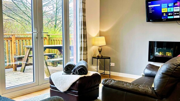 A modern living room with a large TV, a sofa, and a bench with rolled-up towels.