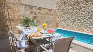A poolside table with food and drinks, a potted plant, and a stone wall. - Can Diana - Villa With Private Pool In Campanet (Campanet, Illes Balears)