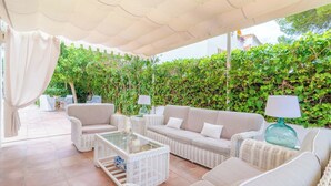 An outdoor seating area with wicker furniture, a glass-top table, and a white canopy. - Can Ferro - Villa With Private Pool In Cala Blava (Cala Blava (llucmajor), Illes Balears)