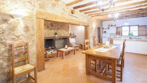 A rustic interior with exposed wooden beams, a stone wall, a fireplace, and a dining area with wooden furniture. - Sa Cova (cova De Rotana) - Villa With Private Pool (Manacor, Illes Balears)