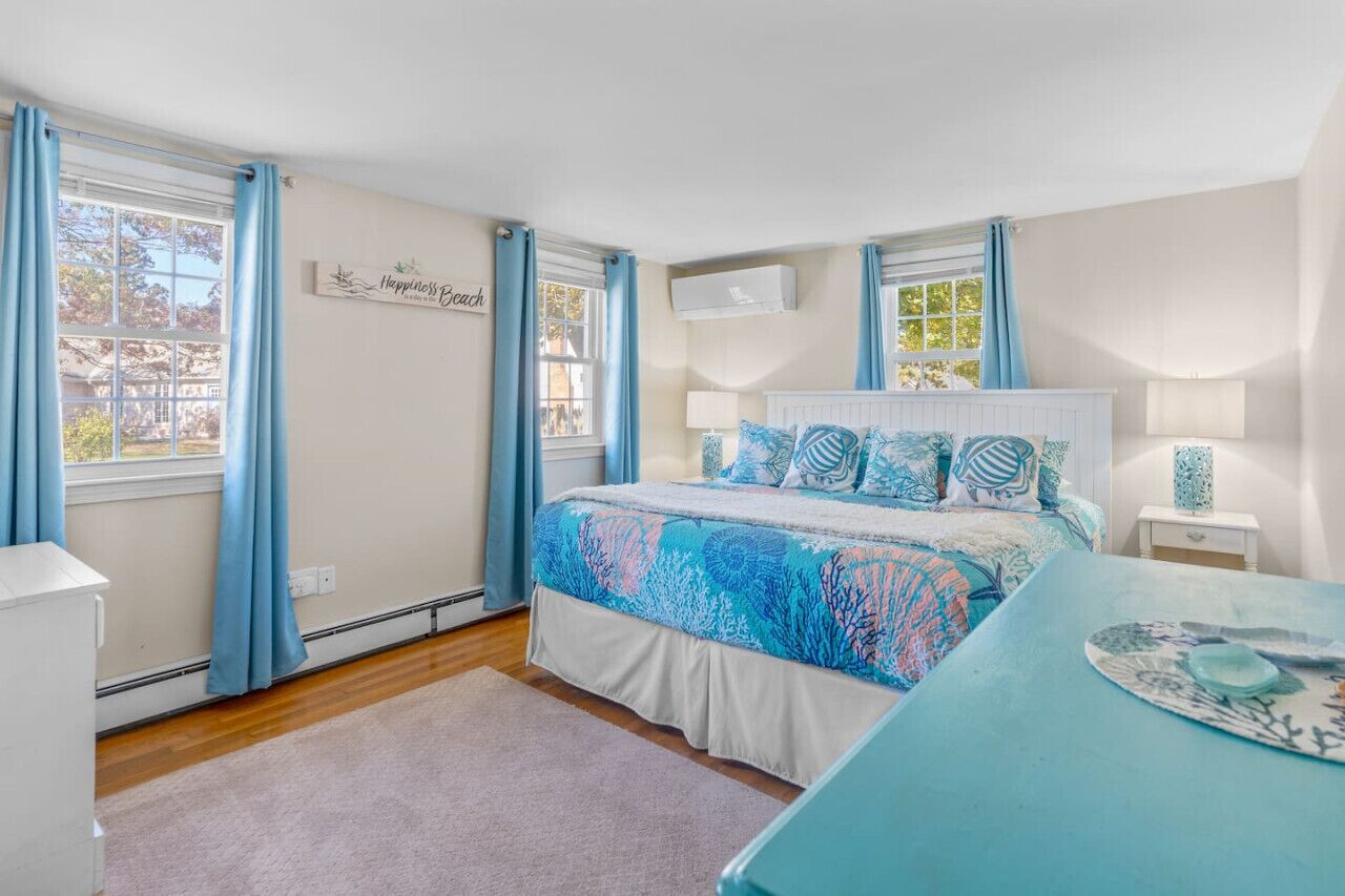 A bedroom with a bed, a nightstand, a dresser, and a window with curtains.