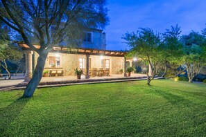Un edificio de piedra con un patio, mobiliario exterior y un césped bien cuidado.