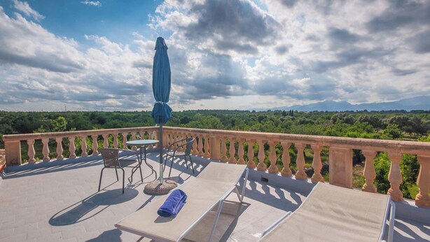 A balcony with a table, chairs, and a sun umbrella overlooking a lush landscape. - Son Morro - Villa With Private Pool. Free Wifi (Santa Margalida, Illes Balears)