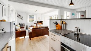 Una cocina moderna con una isla central, un área de comedor con un sofá y un televisor.