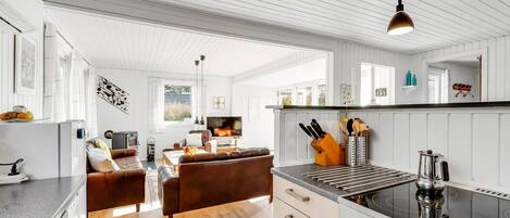 Una cocina moderna con una isla central, un área de comedor con un sofá y un televisor.