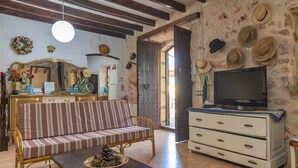 Een gezellige woonkamer met een gestreepte bank, een houten salontafel en een televisie op een dressoir.