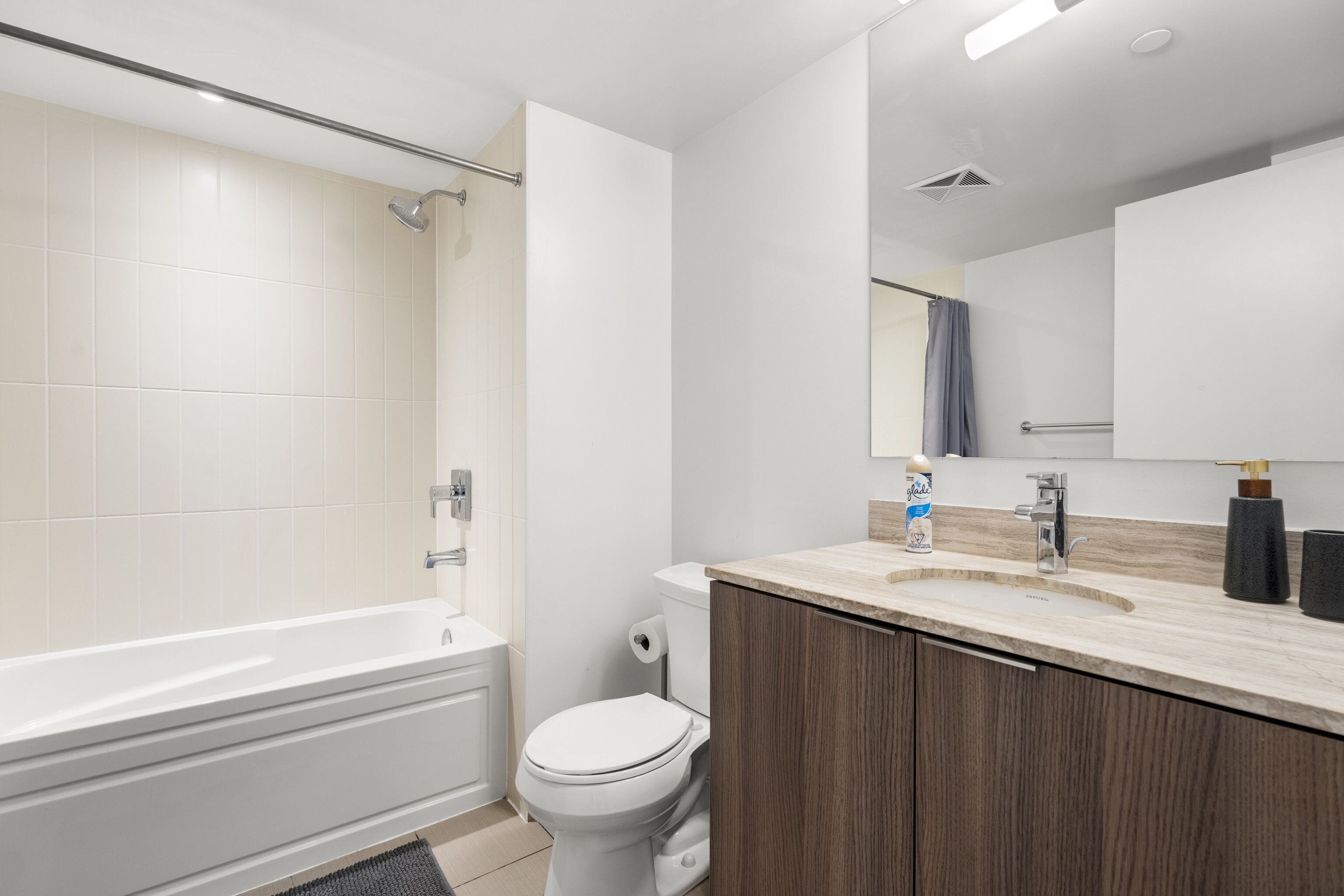 Un baño moderno con bañera, inodoro y tocador con espejo.