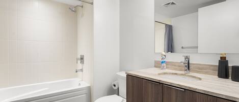 Un baño moderno con bañera, inodoro y tocador con espejo.