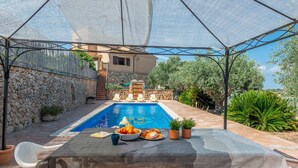 Un espacio exterior cubierto con piscina, paredes de piedra y una mesa con comida.
