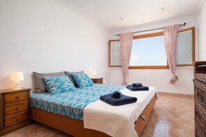 Relax in a cozy space with a large bed, wooden nightstand, and a dresser with mirror.