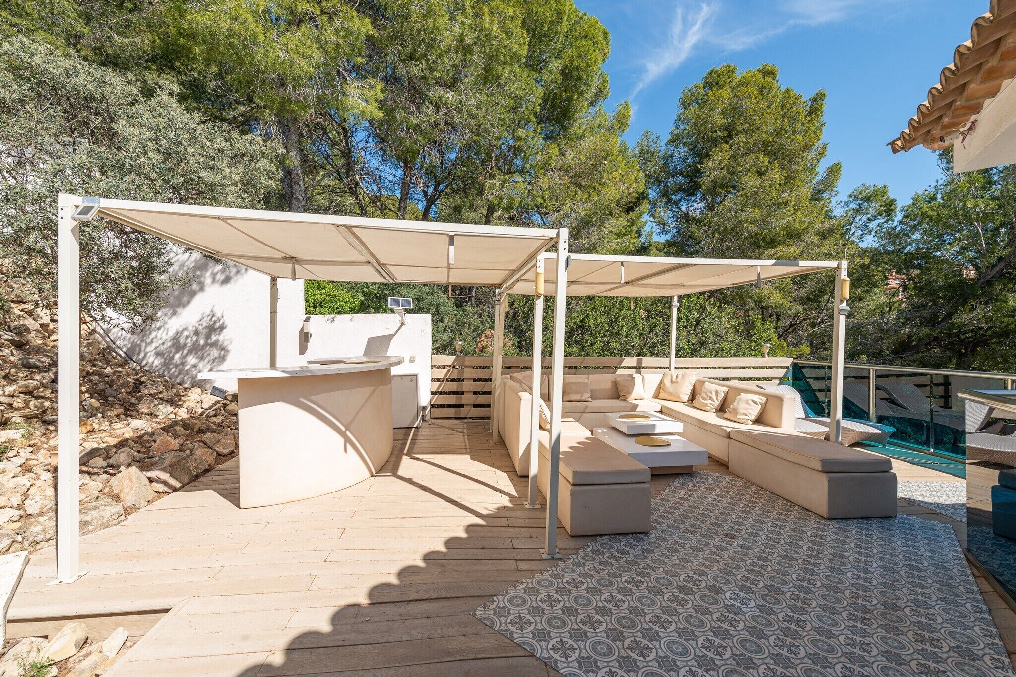 Une terrasse extérieure avec un ensemble de canapés, un coin bar et une piscine.