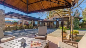 A covered outdoor area with lounge chairs and a pool.