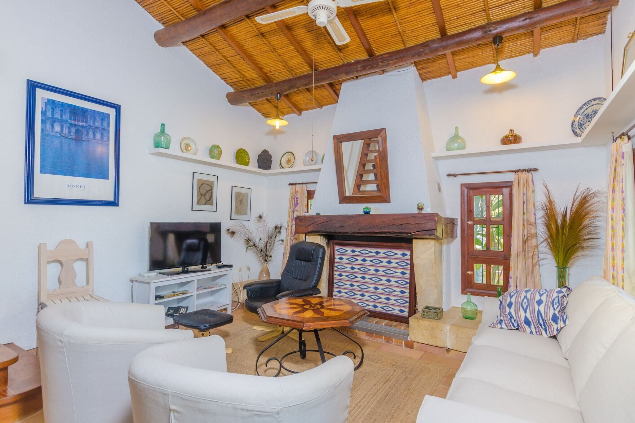 Un salon équipé d’un téléviseur, d’un canapé, de fauteuils, d’une cheminée et d’un ventilateur de plafond.